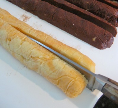 cutting-rolls-of-orange-chocolate-cookie-dough-in-halves-and-quarters-with-floured-knife