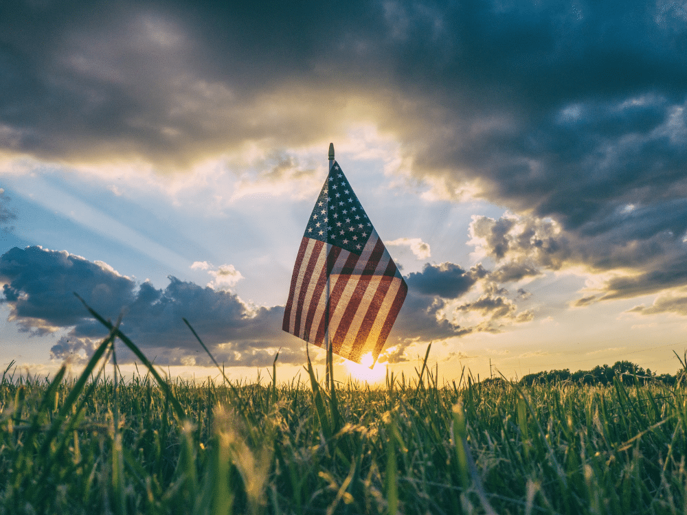 Memorial Day - green grass, blue sky with clouds, sunrise, american flag planted in ground