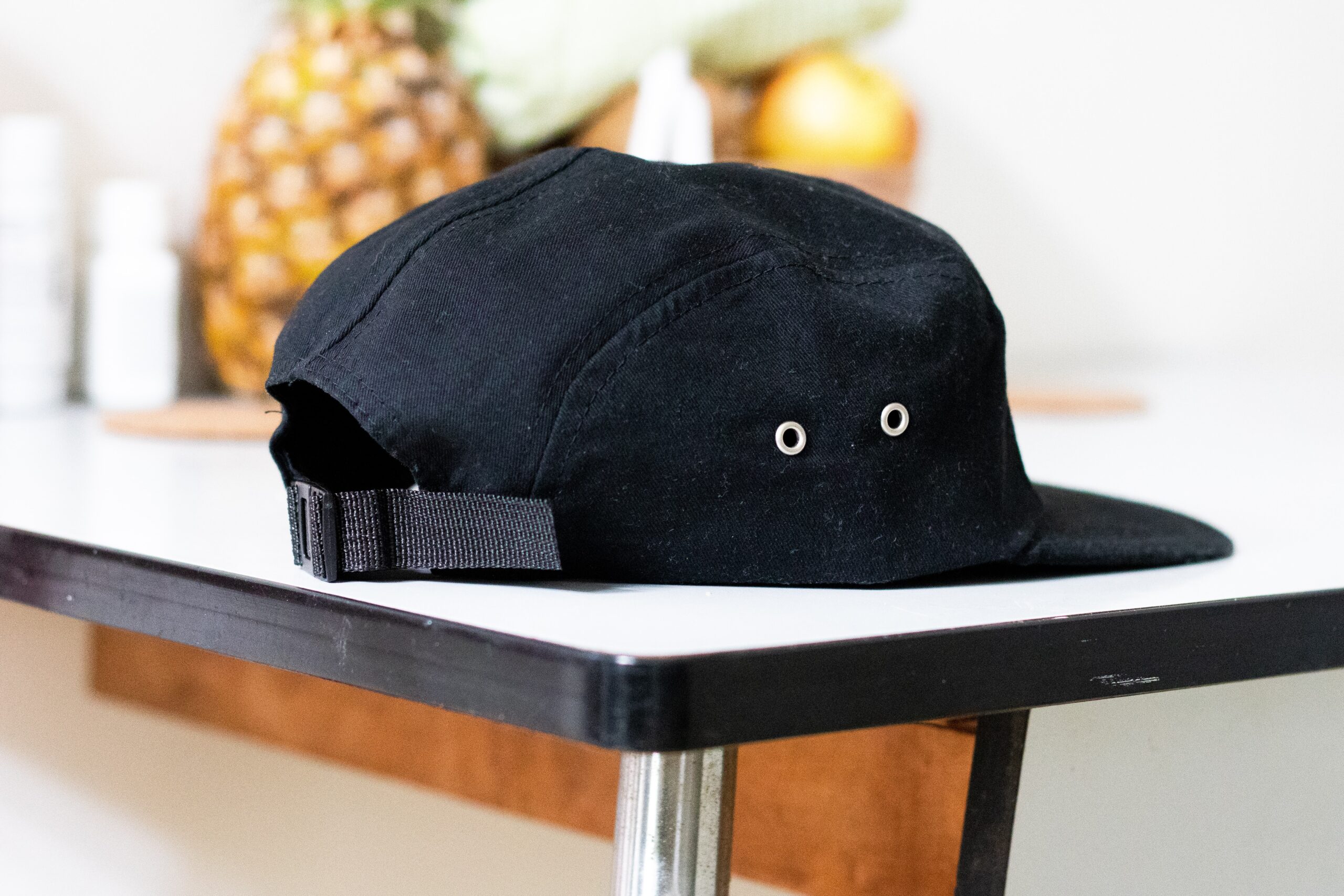 black ball cap on white counter with pineapple in background