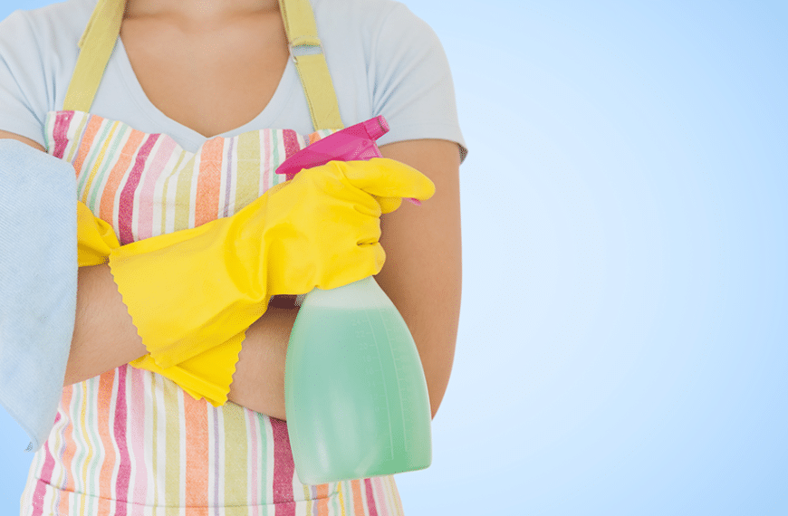 woman wearing yellow gloves and holding spray cleaner and a napkin