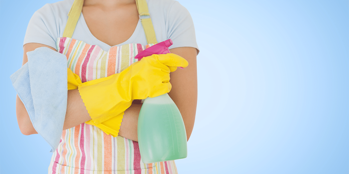 woman wearing yellow gloves and holding spray cleaner and a napkin