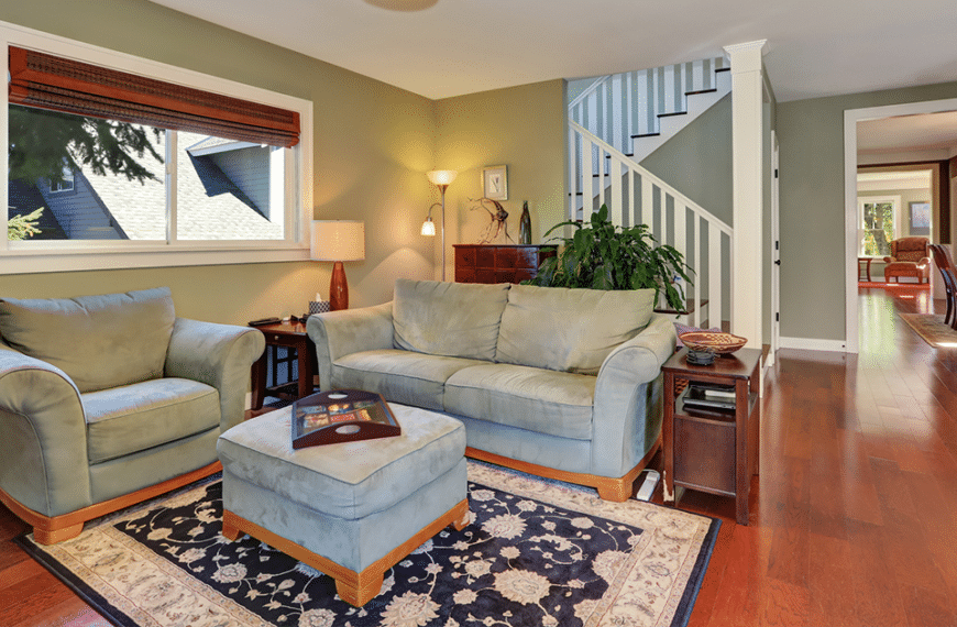 Couch in front of stairs with area rug and ottoman in living room